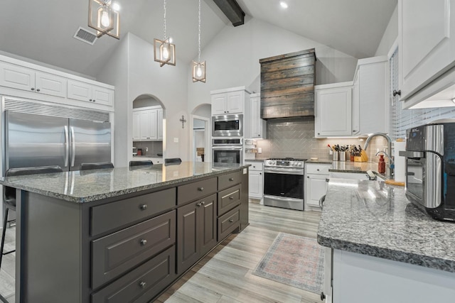 kitchen with dark stone countertops, appliances with stainless steel finishes, a center island, and white cabinets