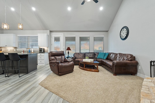 living room with ceiling fan, sink, high vaulted ceiling, and light hardwood / wood-style flooring