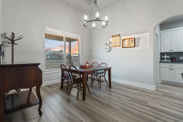 dining room with a towering ceiling, light hardwood / wood-style flooring, and a chandelier