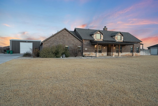 view of front of property with a garage, a porch, an outdoor structure, and a yard