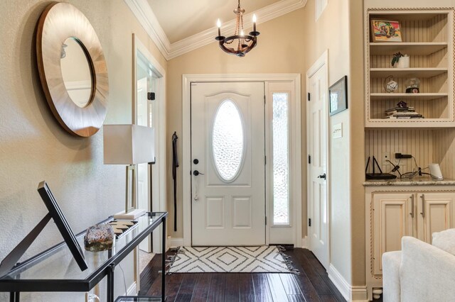 foyer entrance with dark wood-type flooring, ornamental molding, a chandelier, and a healthy amount of sunlight