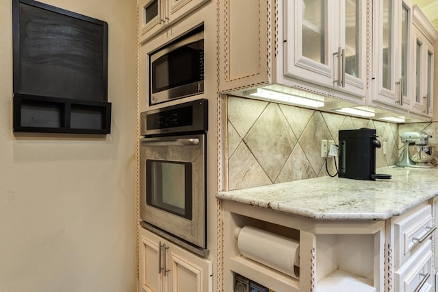 kitchen featuring tasteful backsplash, light stone countertops, and appliances with stainless steel finishes