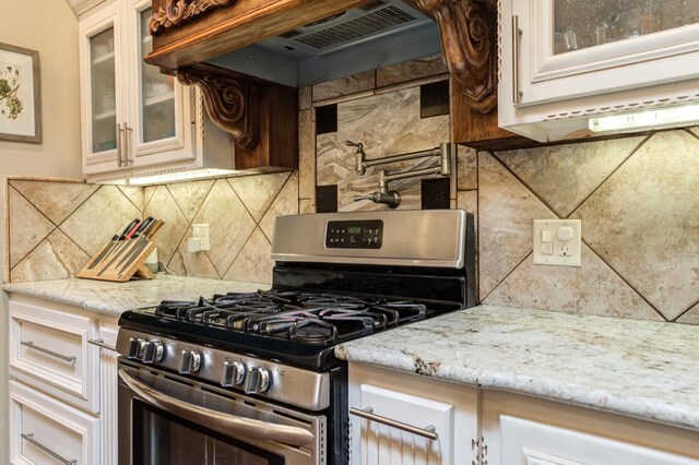 kitchen featuring decorative backsplash, light stone countertops, stainless steel gas range, and custom exhaust hood