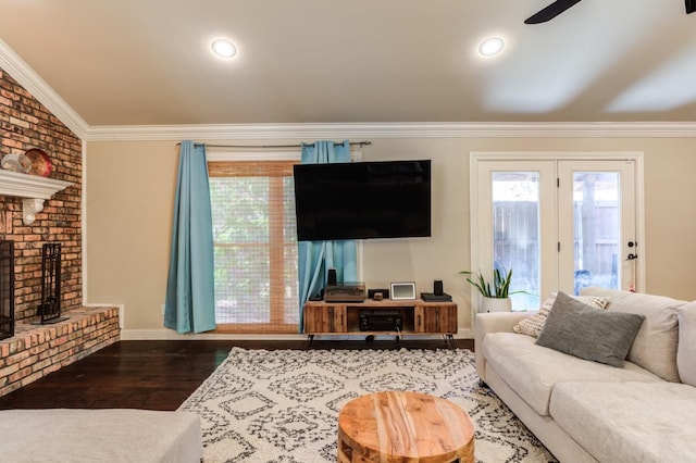 living room with crown molding, a brick fireplace, and dark hardwood / wood-style floors