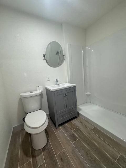 bathroom with walk in shower, vanity, and toilet