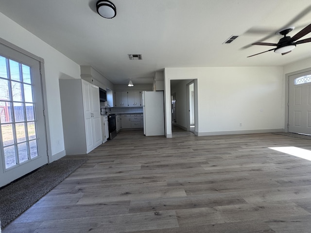 unfurnished living room featuring ceiling fan, a healthy amount of sunlight, and light hardwood / wood-style floors