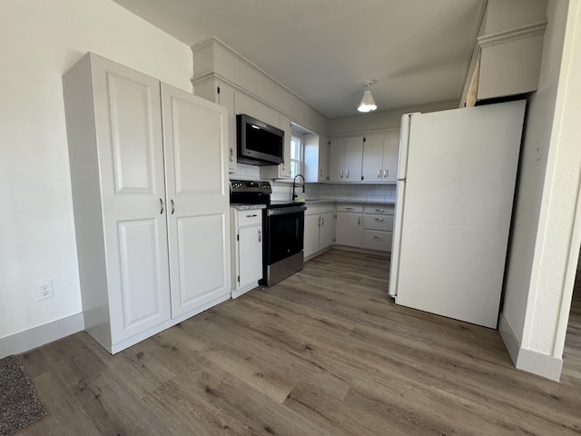 kitchen with white refrigerator, white cabinets, stainless steel range with electric cooktop, and light hardwood / wood-style flooring