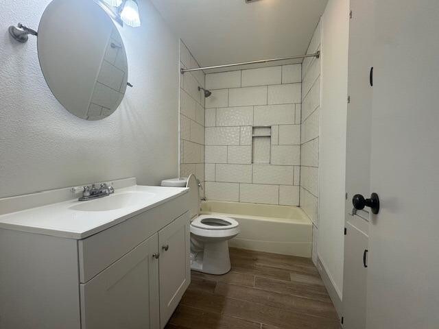 full bathroom with vanity, tiled shower / bath, hardwood / wood-style flooring, and toilet