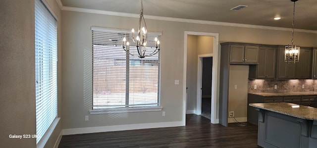 kitchen with crown molding, light stone countertops, an inviting chandelier, and decorative light fixtures