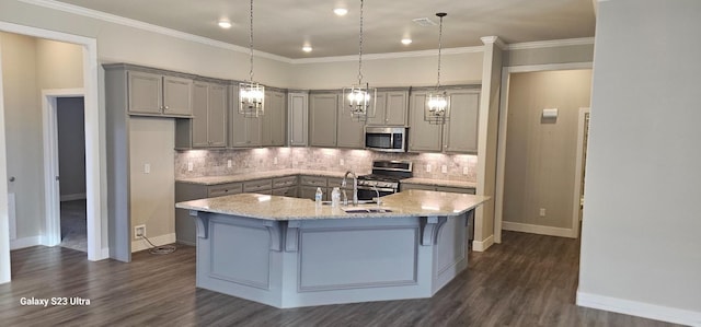 kitchen with an island with sink, backsplash, stainless steel appliances, crown molding, and light stone countertops