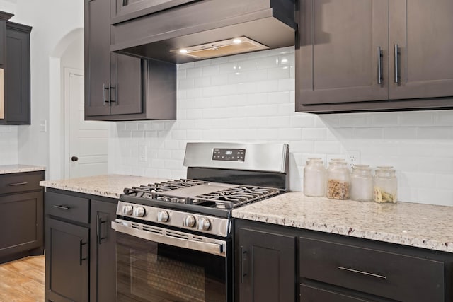 3615 121st St, Lubbock, TX 79423 - kitchen featuring stainless steel range with gas stovetop, wall chimney exhaust hood, tasteful backsplash, and arched walkways