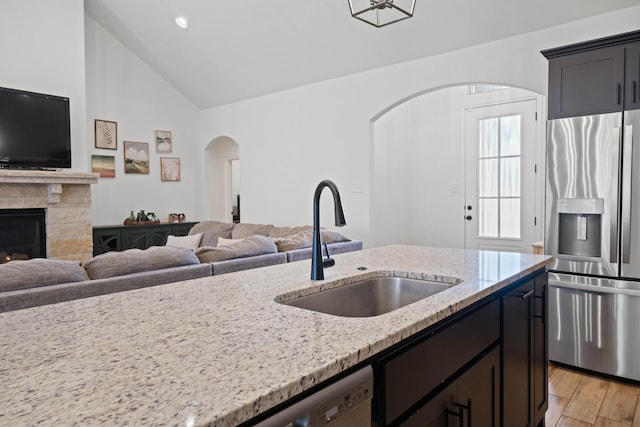 3615 121st St, Lubbock, TX 79423 - kitchen with stainless steel fridge with ice dispenser, open floor plan, arched walkways, light stone counters, and high vaulted ceiling