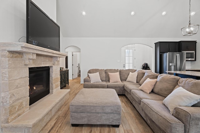 3615 121st St, Lubbock, TX 79423 - living room featuring arched walkways, a stone fireplace, light wood-type flooring, recessed lighting, and a chandelier