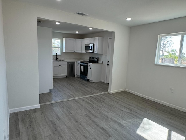 kitchen featuring range with electric cooktop, white cabinetry, sink, dishwashing machine, and light hardwood / wood-style floors