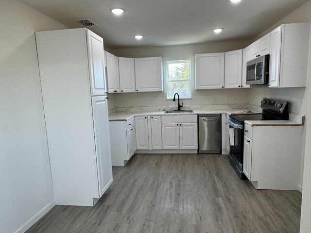 kitchen featuring white cabinetry, stainless steel appliances, sink, and light wood-type flooring