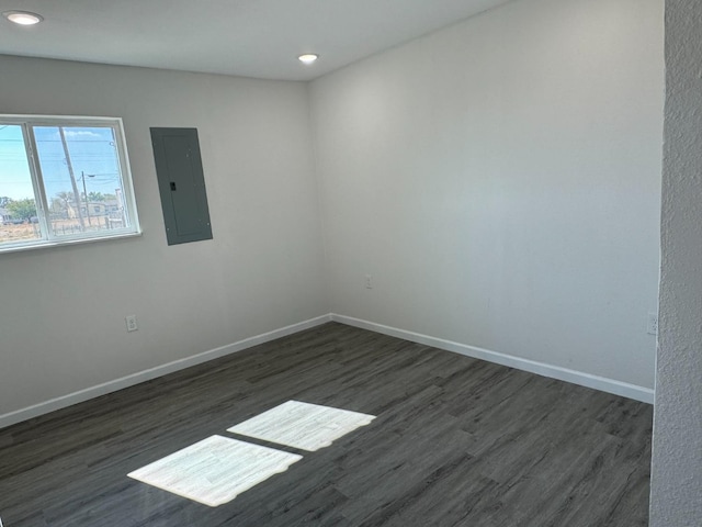 empty room with dark hardwood / wood-style floors and electric panel