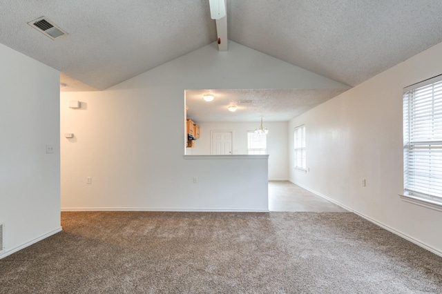 empty room with a chandelier, vaulted ceiling with beams, light carpet, and a textured ceiling