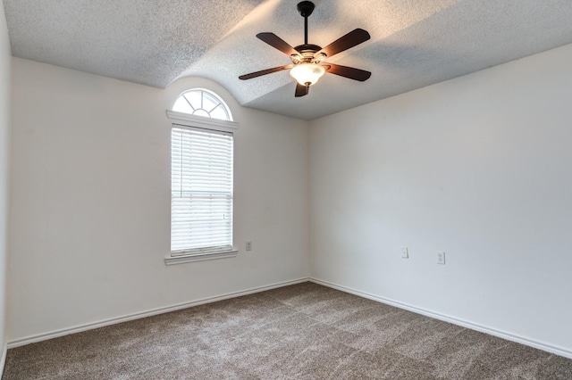 empty room featuring vaulted ceiling, carpet flooring, a textured ceiling, and ceiling fan