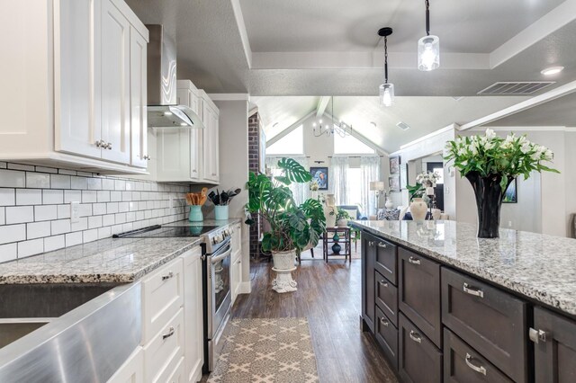 kitchen featuring stainless steel electric stove, pendant lighting, white cabinets, light stone countertops, and wall chimney exhaust hood