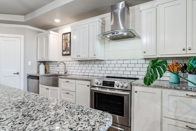 kitchen featuring light stone counters, white cabinets, stainless steel appliances, and wall chimney exhaust hood