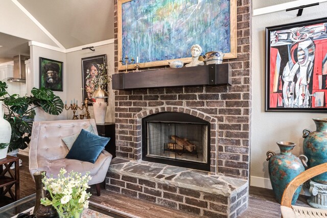 living room featuring hardwood / wood-style flooring, vaulted ceiling, and a brick fireplace