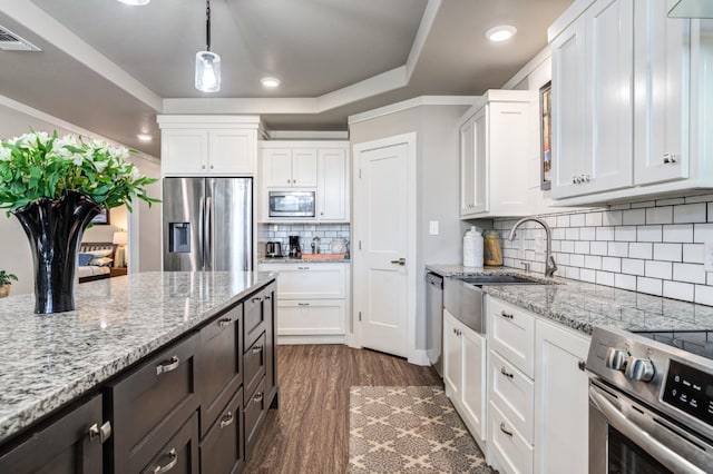 kitchen featuring stainless steel appliances, white cabinetry, hanging light fixtures, and light stone counters