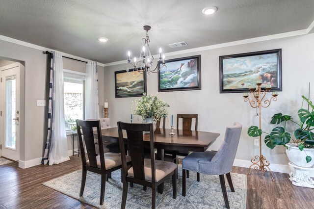 dining area featuring ornamental molding, dark hardwood / wood-style floors, a notable chandelier, and a textured ceiling