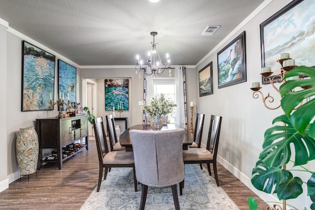 dining space featuring a notable chandelier, dark wood-type flooring, ornamental molding, and a textured ceiling