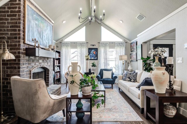 living room with hardwood / wood-style floors, vaulted ceiling, a brick fireplace, and a notable chandelier