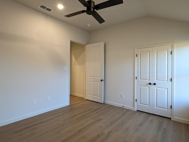 unfurnished bedroom with ceiling fan, vaulted ceiling, a closet, and light wood-type flooring