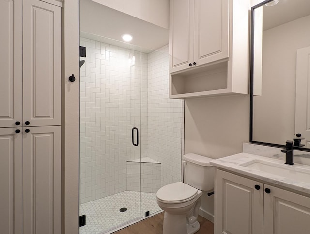 bathroom with toilet, hardwood / wood-style floors, vanity, and a shower with shower door