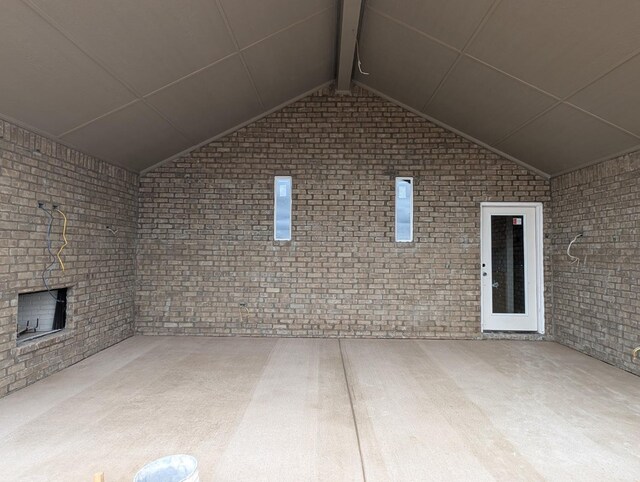 interior space featuring brick wall and lofted ceiling