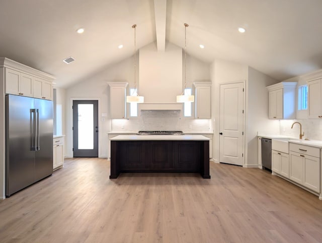 kitchen with sink, white cabinetry, hanging light fixtures, stainless steel appliances, and a kitchen island