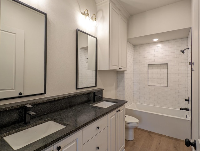 full bathroom with vanity, hardwood / wood-style flooring, toilet, and tiled shower / bath