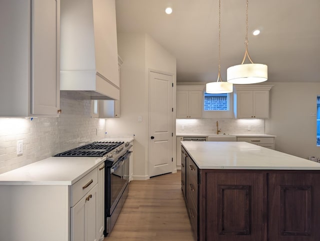 kitchen featuring pendant lighting, white cabinetry, stainless steel gas range oven, and a kitchen island