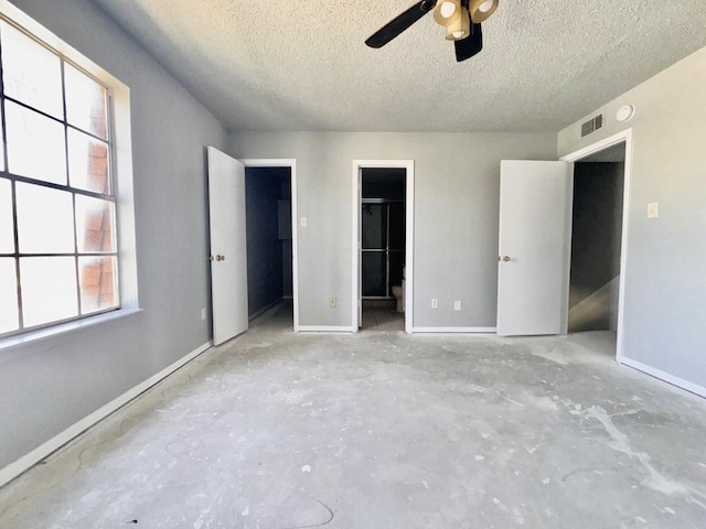 unfurnished bedroom with ceiling fan, a spacious closet, a textured ceiling, and a closet