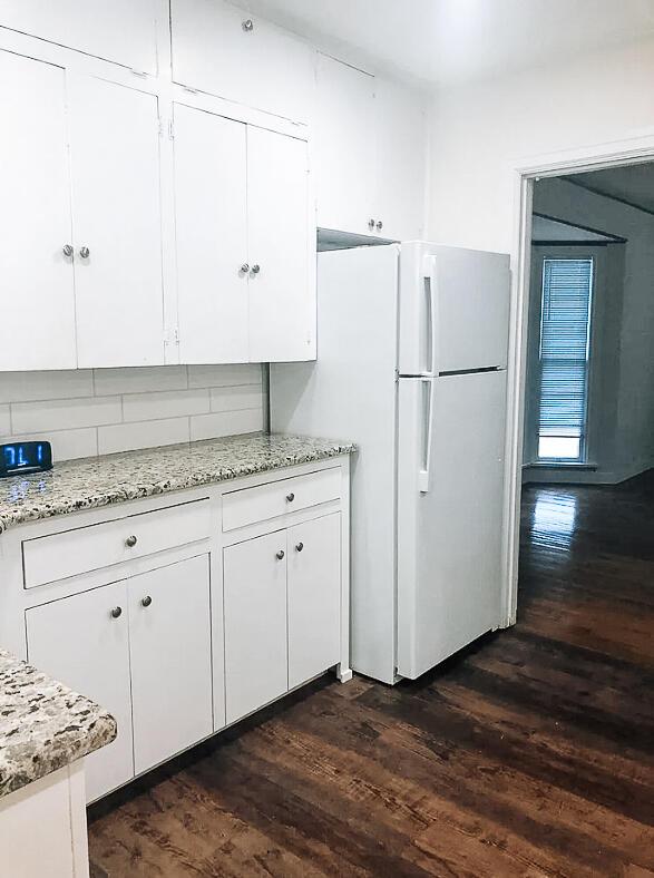 2003 30th St, Lubbock, TX 79411 - kitchen with freestanding refrigerator, dark wood-style floors, white cabinets, and tasteful backsplash