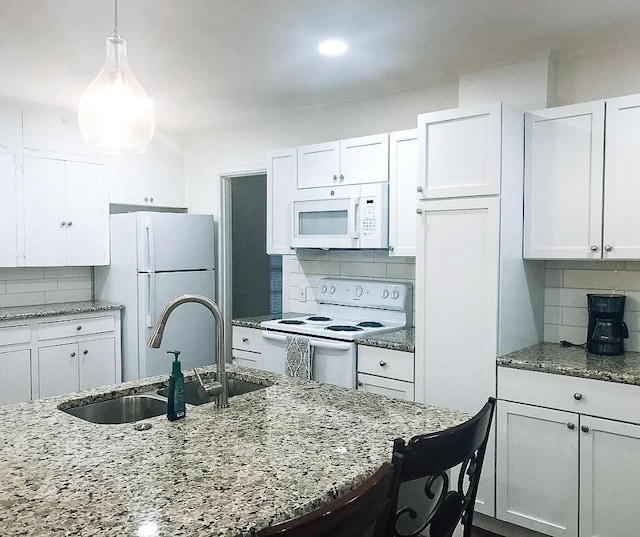 2003 30th St, Lubbock, TX 79411 - kitchen featuring white appliances, decorative backsplash, white cabinets, and light stone countertops
