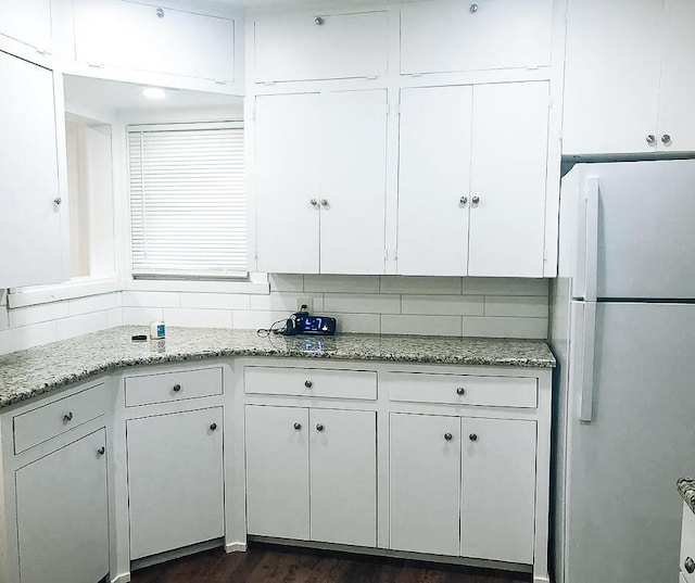 2003 30th St, Lubbock, TX 79411 - kitchen with freestanding refrigerator, white cabinetry, light stone countertops, and dark wood-style floors