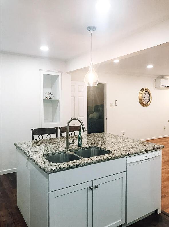 2003 30th St, Lubbock, TX 79411 - kitchen featuring dishwasher, a wall unit AC, an island with sink, light stone counters, and recessed lighting