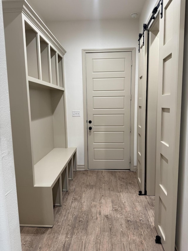 5414 112th St, Lubbock, TX 79424 - mudroom with a barn door, wood finished floors, and baseboards