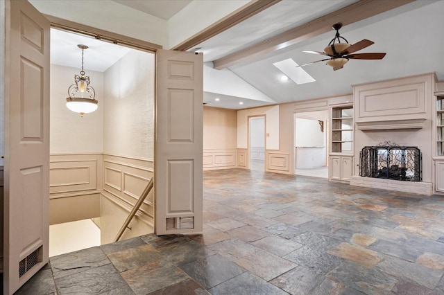 interior space featuring a brick fireplace, vaulted ceiling with skylight, ceiling fan, and decorative light fixtures