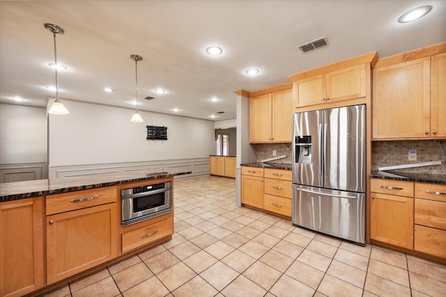 kitchen featuring light tile patterned floors, appliances with stainless steel finishes, hanging light fixtures, tasteful backsplash, and light brown cabinetry