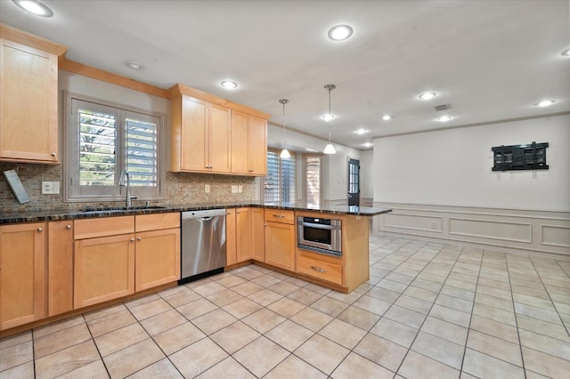 kitchen with appliances with stainless steel finishes, sink, dark stone counters, hanging light fixtures, and kitchen peninsula