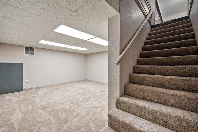 basement with a drop ceiling and carpet