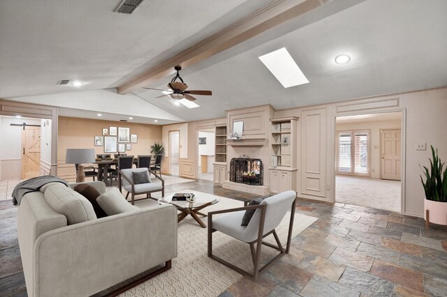 living room with a barn door, ceiling fan, and vaulted ceiling with skylight