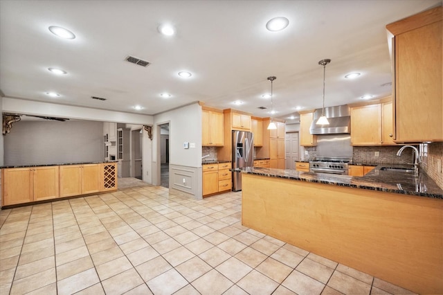 kitchen featuring wall chimney exhaust hood, sink, hanging light fixtures, appliances with stainless steel finishes, and kitchen peninsula