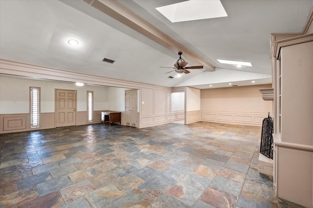 unfurnished living room featuring ceiling fan and vaulted ceiling with skylight