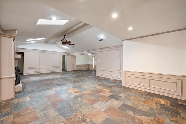 unfurnished living room featuring ceiling fan and vaulted ceiling with skylight