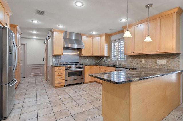 kitchen featuring sink, stainless steel appliances, decorative light fixtures, kitchen peninsula, and wall chimney exhaust hood